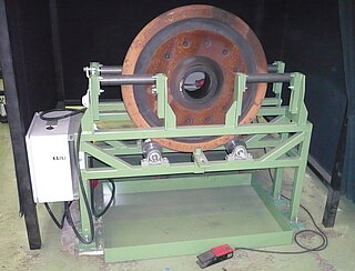 Rolling device for individual MT (magnetic particle) wheel inspection: For this purpose, the wheel discs are positioned in upright position on the device, where they are safely guided laterally, while being set into regular rotation.