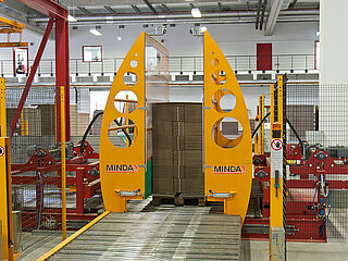 Pallet loading station with feeding of empty palletts; for single product stack:  On the pallet there is a product stack, the alignment walls are moved together to align the stack.