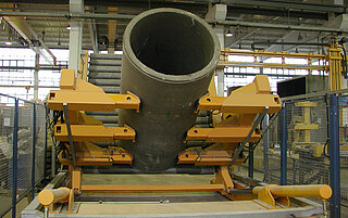 Tilting car with concrete pipes, which takes the pipe with holding arms. The pipe is set up and can be removed by an indoor crane.