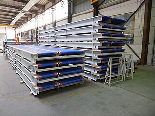 Plastic chain conveyors with blue chain: two stacks side by side. On the left side 4 plastic chain conveyors are stacked on top of each other, on the right side there are 8. 