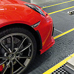 The red front of a car from the side, still in a production line