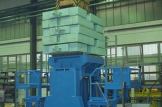 The wheelset drop (wheel changing device) is used to lift and lower rail vehicle cars for changing the bolster springs from bogies and for transporting rail vehicle parts (max. 25 t) as well as for transporting the dismantled wheelsets. The picture shows loading/ stress test with a stack of concrete slabs during the factory acceptance test.