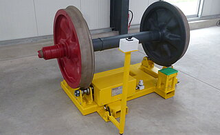 Mobile turning device with wheelset: Four profile rollers, one of them is driven, support the wheelset. The device is equipped with so-called forklift shoes to enable the entire unit to be transported by forklift truck. In order to additionally store this special device in a space-saving manner, the control console can be retracted.