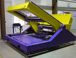 Assembly and tilting device for transformers (45 Degrees tilted, without Transformer): The mobile transformer tilting device consists of a base frame on which a pivot-mounted tilting frame is fixed. The base frame stands on adjustable feet. At the front part of the tilting frame (on the right side of the picture) a support plate is mounted which serves as a limit stop or footprint for the tilted transformer. 