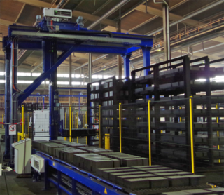 Gantry for automated unloading loads on pallets from trolleys: the loaded pallets with refractory bricks are placed onto a roller conveyor which transports the refractory bricks to a packaging line.